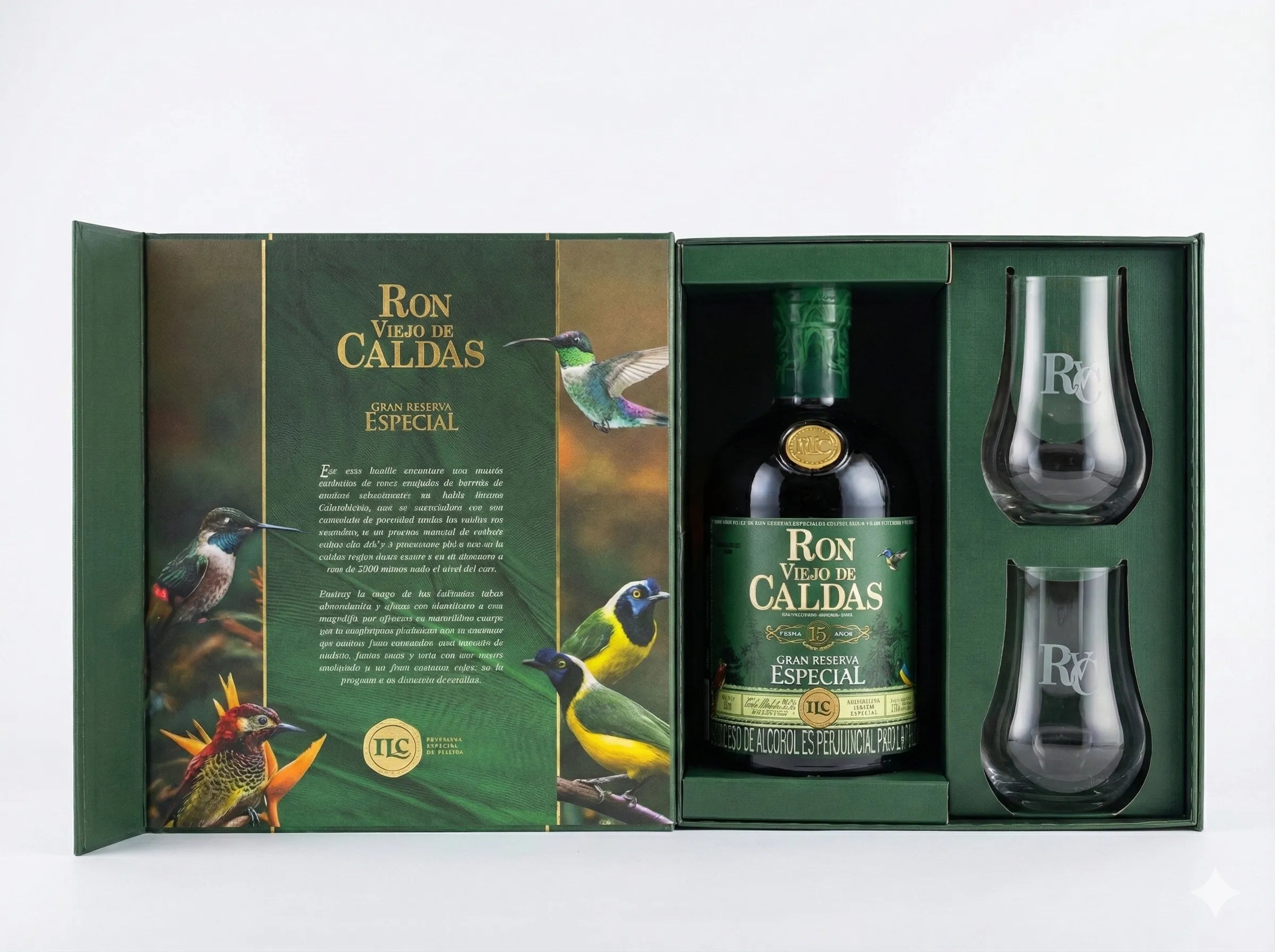 Estuche verde de lujo abierto de Ron Viejo de Caldas Gran Reserva Especial. Contiene una botella, dos copas de cristal grabadas y una tapa interior decorada con texto y coloridas ilustraciones de aves sobre fondo blanco.