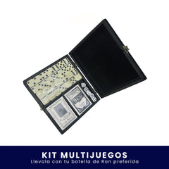 Estuche negro abierto que contiene un kit de juegos de mesa con fichas de dominó, dados y una baraja de cartas sobre fondo blanco. En la parte inferior tiene un banner azul con el texto "Kit Multijuegos Llévalo con tu botella de Ron preferida