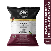 Empaque frontal de papas chips Monte Rojo, edición especial sabor Ron Viejo de Caldas de 100g. El diseño incluye ilustraciones de aves típicas colombianas sobre un fondo de tonos negro, crema y vinotinto, destacando la colaboración "Tributo a Colombia" y el logo de la marca.