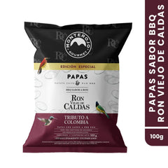 Empaque frontal de papas chips Monte Rojo, edición especial sabor Ron Viejo de Caldas de 100g. El diseño incluye ilustraciones de aves típicas colombianas sobre un fondo de tonos negro, crema y vinotinto, destacando la colaboración "Tributo a Colombia" y el logo de la marca.