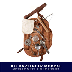Morral de tela color café que sirve como estuche organizador para herramientas de coctelería. Incluye diversos utensilios metálicos de bar como coladores, cucharas y accesorios, dispuestos sobre el morral contra un fondo blanco. En la parte inferior tiene un banner azul con el texto "Kit Bartender Morral Llévalo con tu botella de Ron preferida".