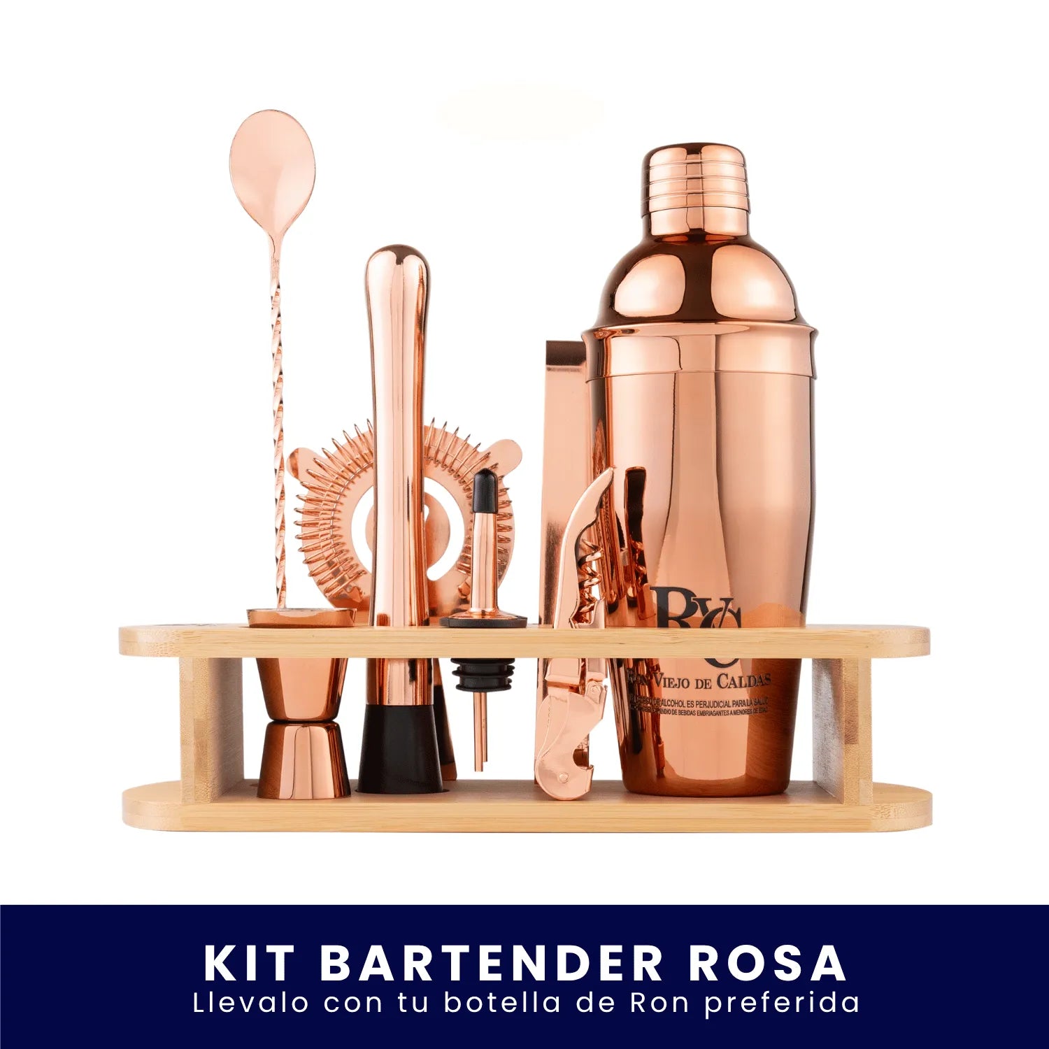 Set de coctelería con acabado en oro rosa que incluye una coctelera, cuchara, medidor y otros utensilios, organizados en un soporte de madera sobre fondo blanco. En la parte inferior tiene un banner azul con el texto "Kit Bartender Rosa Llévalo con tu botella de Ron preferida".