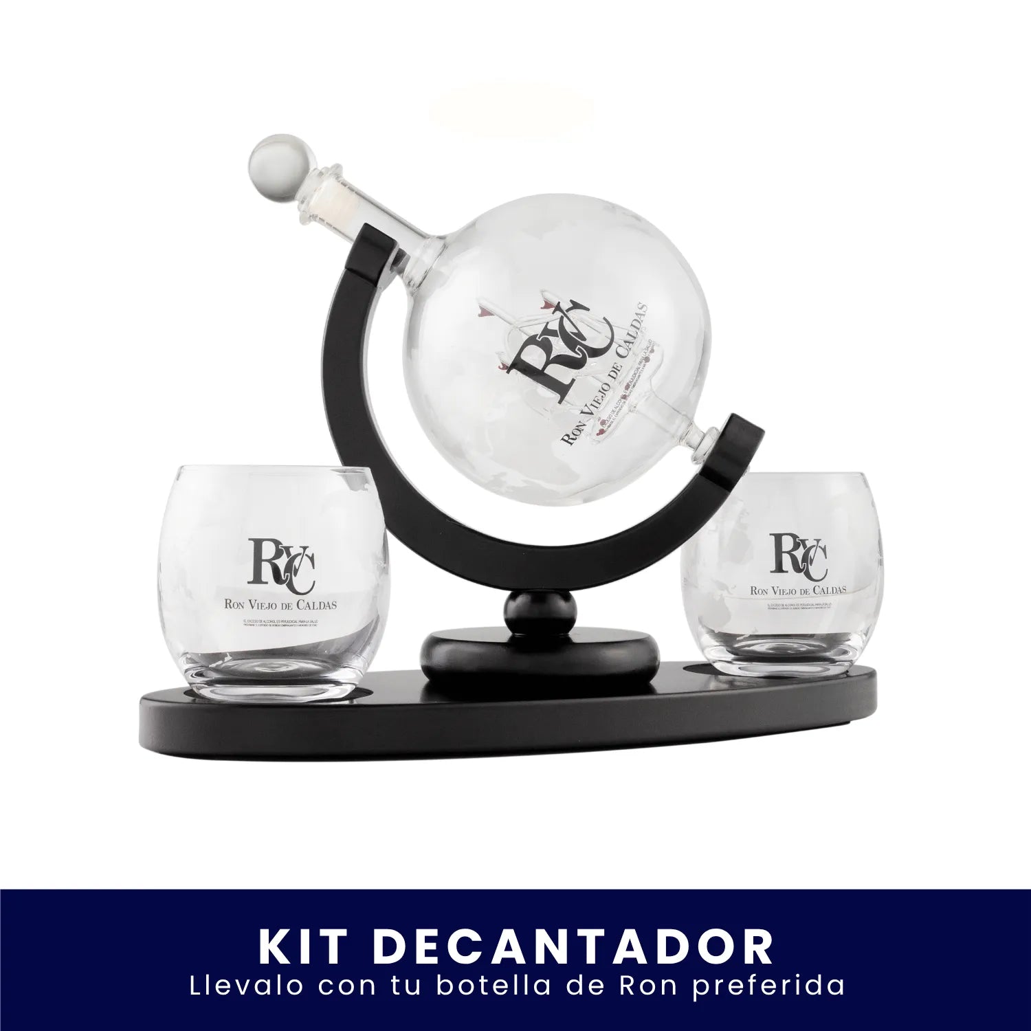 Set de bar que incluye un decantador de vidrio esférico montado sobre un soporte giratorio y dos vasos de cristal, todos con el logo de Ron Viejo de Caldas grabado, sobre fondo blanco. En la parte inferior tiene un banner azul con el texto "Kit Decantador Llévalo con tu botella de Ron preferida".