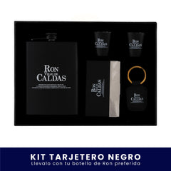 Set de regalo en caja negra que incluye una licorera de bolsillo negra, dos vasos tipo shot negros, un tarjetero y un llavero, todos con el logo de Ron Viejo de Caldas, sobre fondo blanco. En la parte inferior tiene un banner azul con el texto "Kit Tarjetero Negro Llévalo con tu botella de Ron preferida".